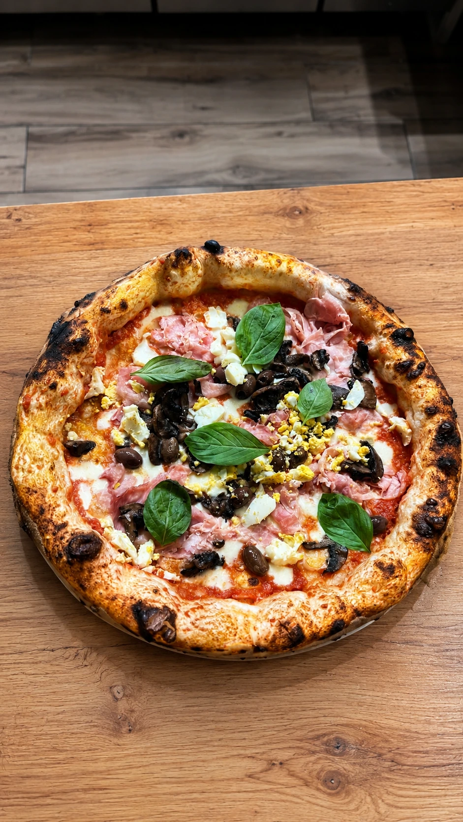 Pizza contemporanea con cornicione alto, prosciutto, funghi e olive
